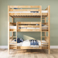 Light natural wood triple bunk bed with ladders, white mattresses and blue bedding in a space-saving modern kids' bedroom with sage green wall and hardwood floor