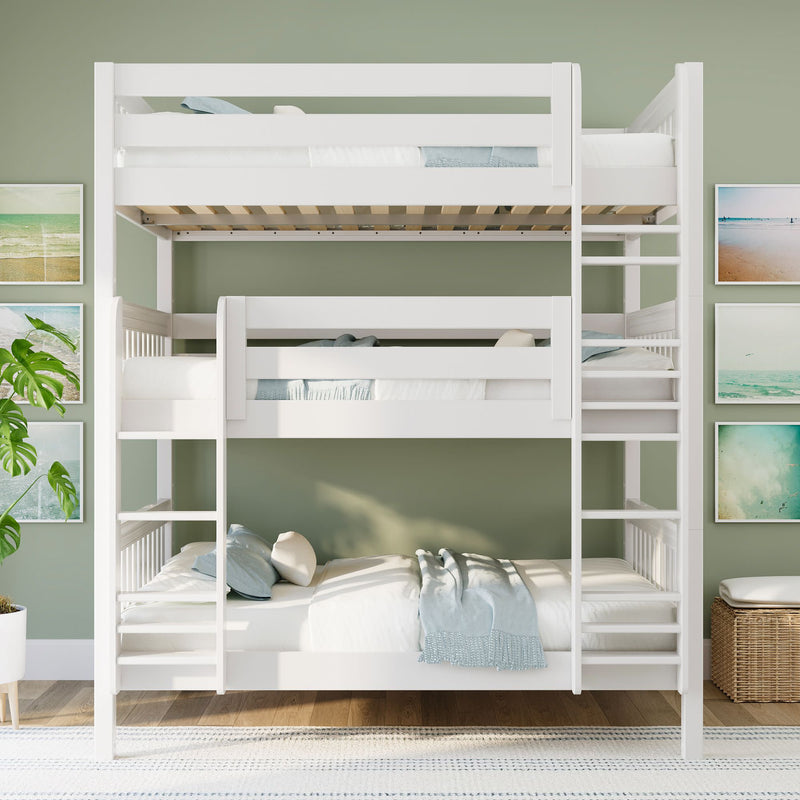 White triple bunk bed in modern coastal kids bedroom with green accent wall, beach wall art, light wood floor and wicker storage.