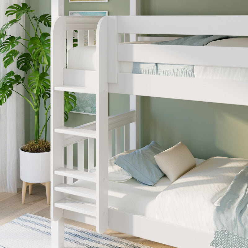 White wooden twin-over-twin bunk bed with ladder in children's bedroom, green accent wall, potted plant and blue pillows
