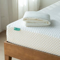 Gel memory foam mattress with white sheet on wooden bed frame.