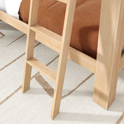 Close-up of a light wood bunk bed ladder with two steps, brown bedding and a textured beige area rug