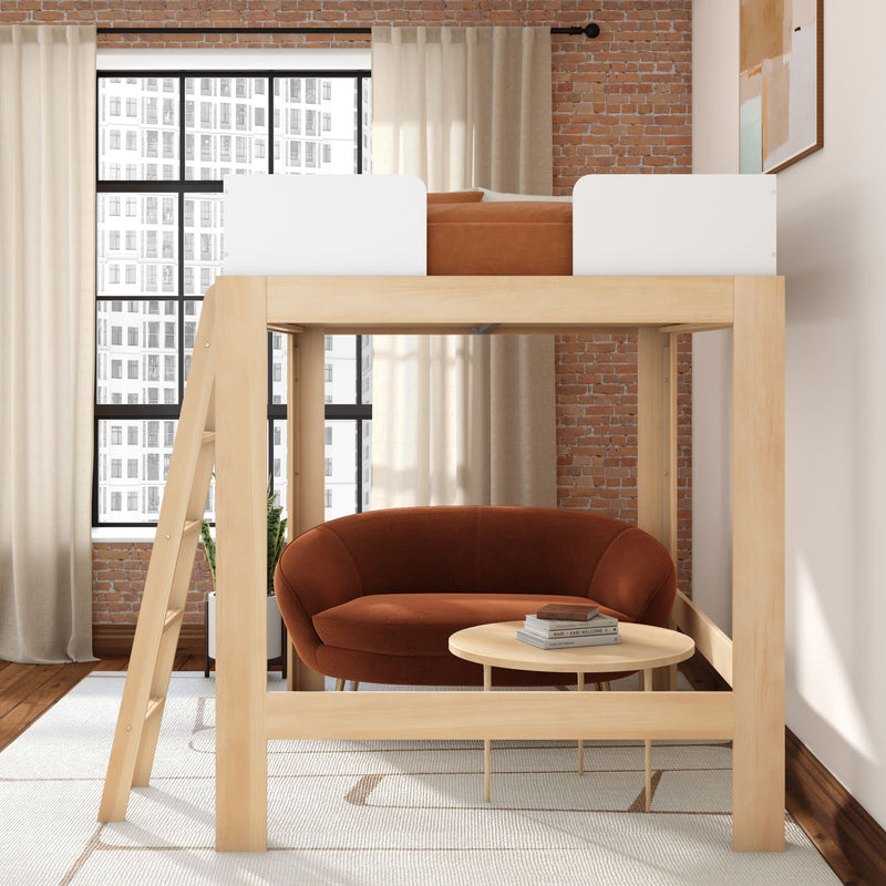 Modern light-wood loft bed with ladder and white safety rails above a cozy rust-colored loveseat and round coffee table in an industrial-style apartment with exposed brick wall and large city-view windows