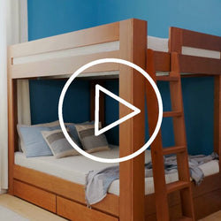 Modern solid wood bunk bed with ladder and built-in storage drawers in a kids' bedroom with navy blue accent wall and striped pillows (video thumbnail)