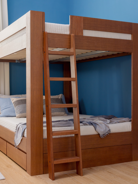 Solid wood twin-over-full bunk bed with ladder and built-in storage drawers in modern blue-walled bedroom on hardwood floor