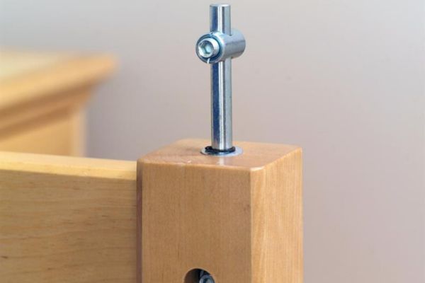 Wooden furniture leg with metal adjusting screw on a neutral background.