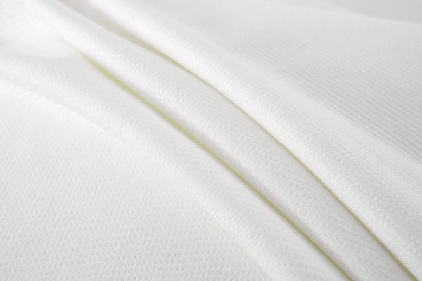 Close-up of white breathable moisture-wicking performance fabric texture with fine athletic mesh weave.