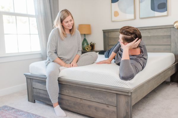 Two people on a bed in a bedroom setting.