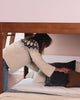 Adults adding bedding to a bottom bunk of an L-shaped bunk bed and socializing together on the bed.